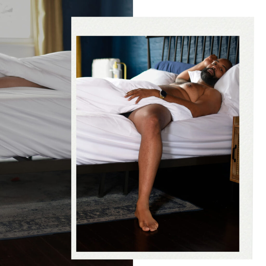 Black man laying in bed with white duvet cover