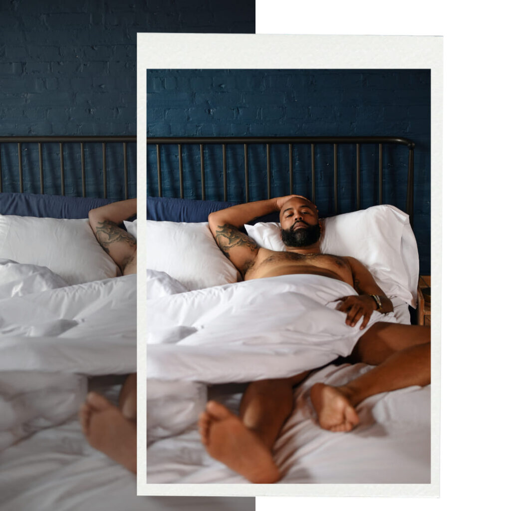 Black man laying in bed with white duvet cover